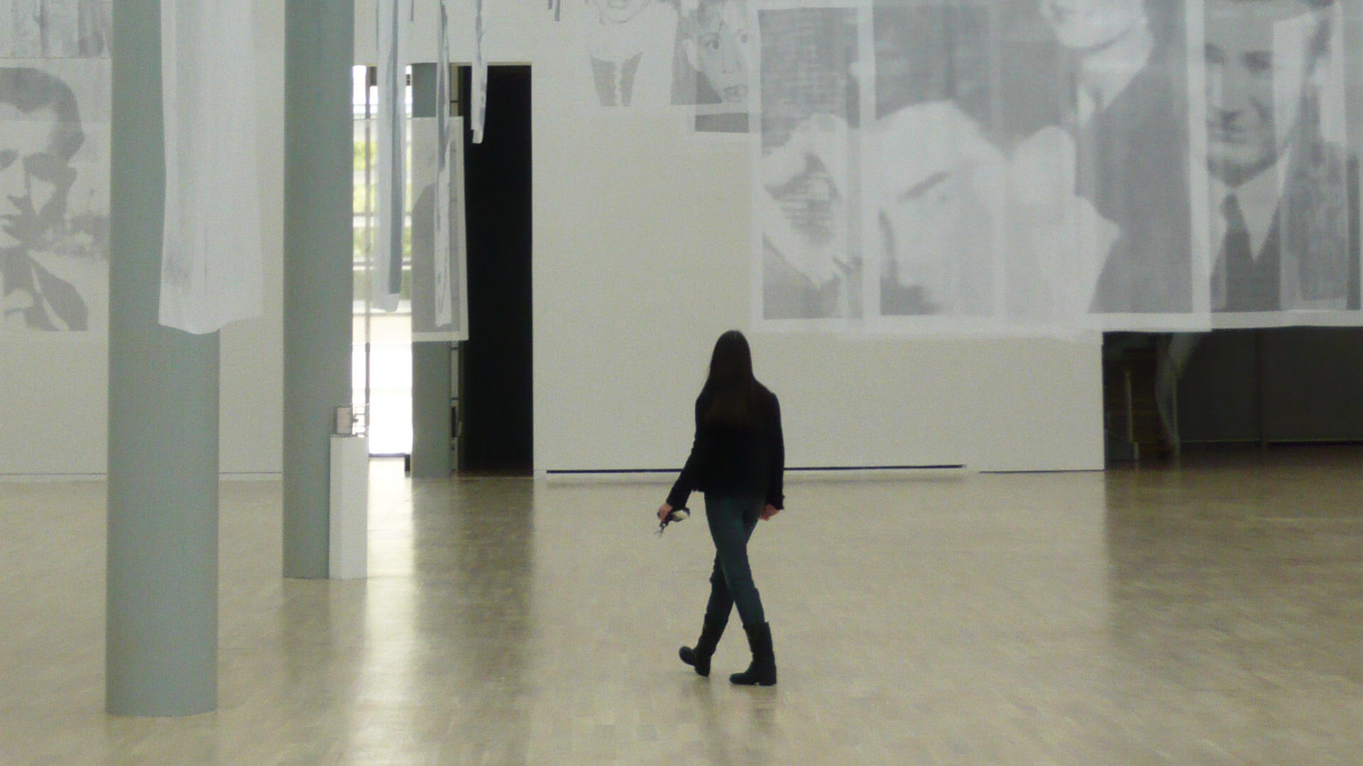 Eine Frau, schwarz gekleidet durchwandert eine Kunstausstellung